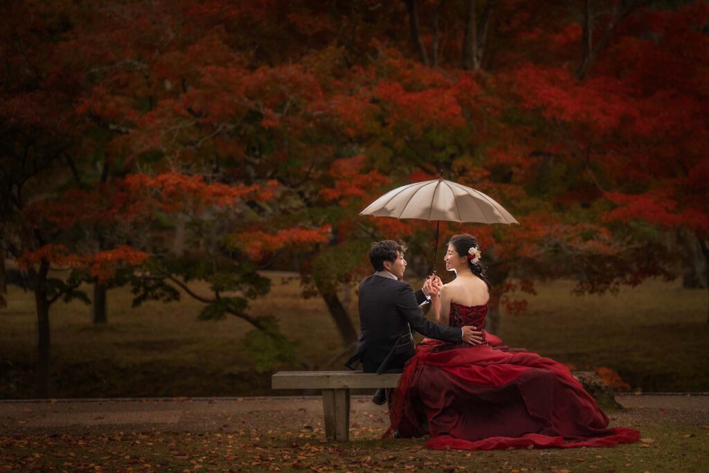 奈良公園の紅葉と赤いドレスのカップル
